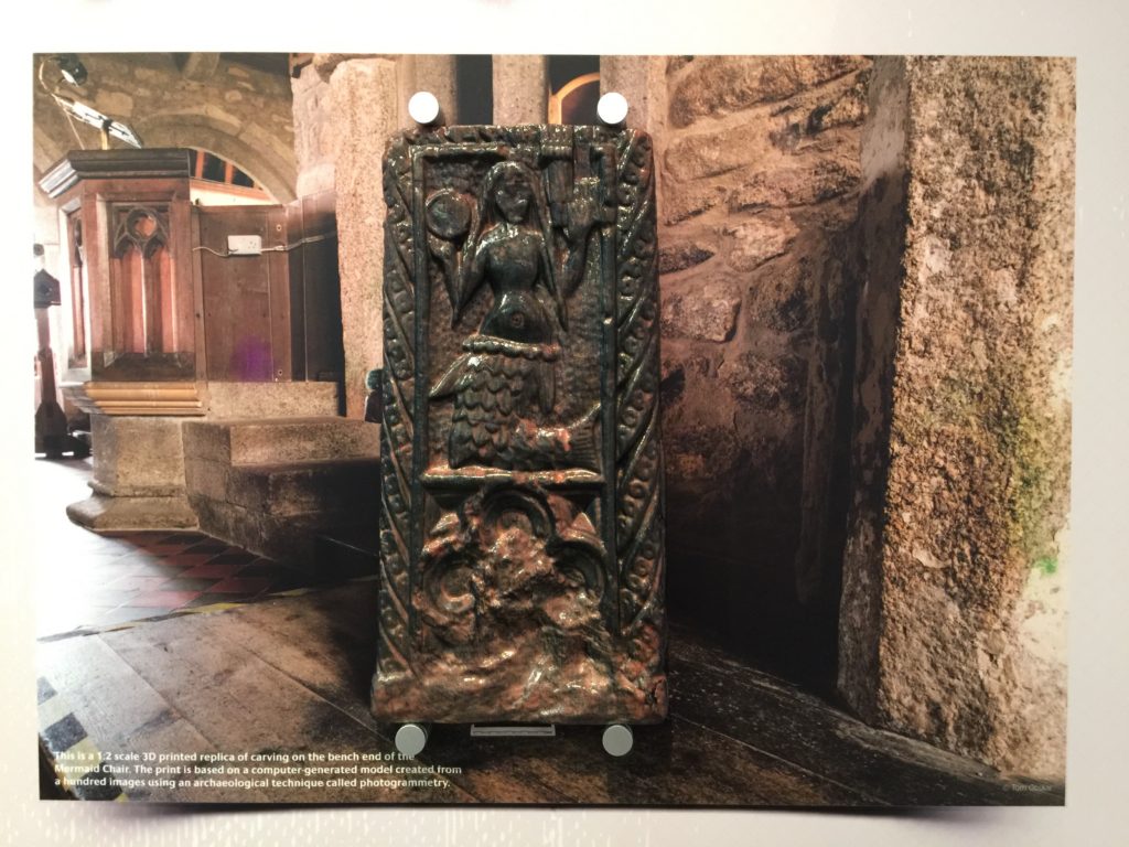 3D printed replica of the Mermaid of Zennor medieval bench end mounted over a photograph of the real bench in the church of St Senara.